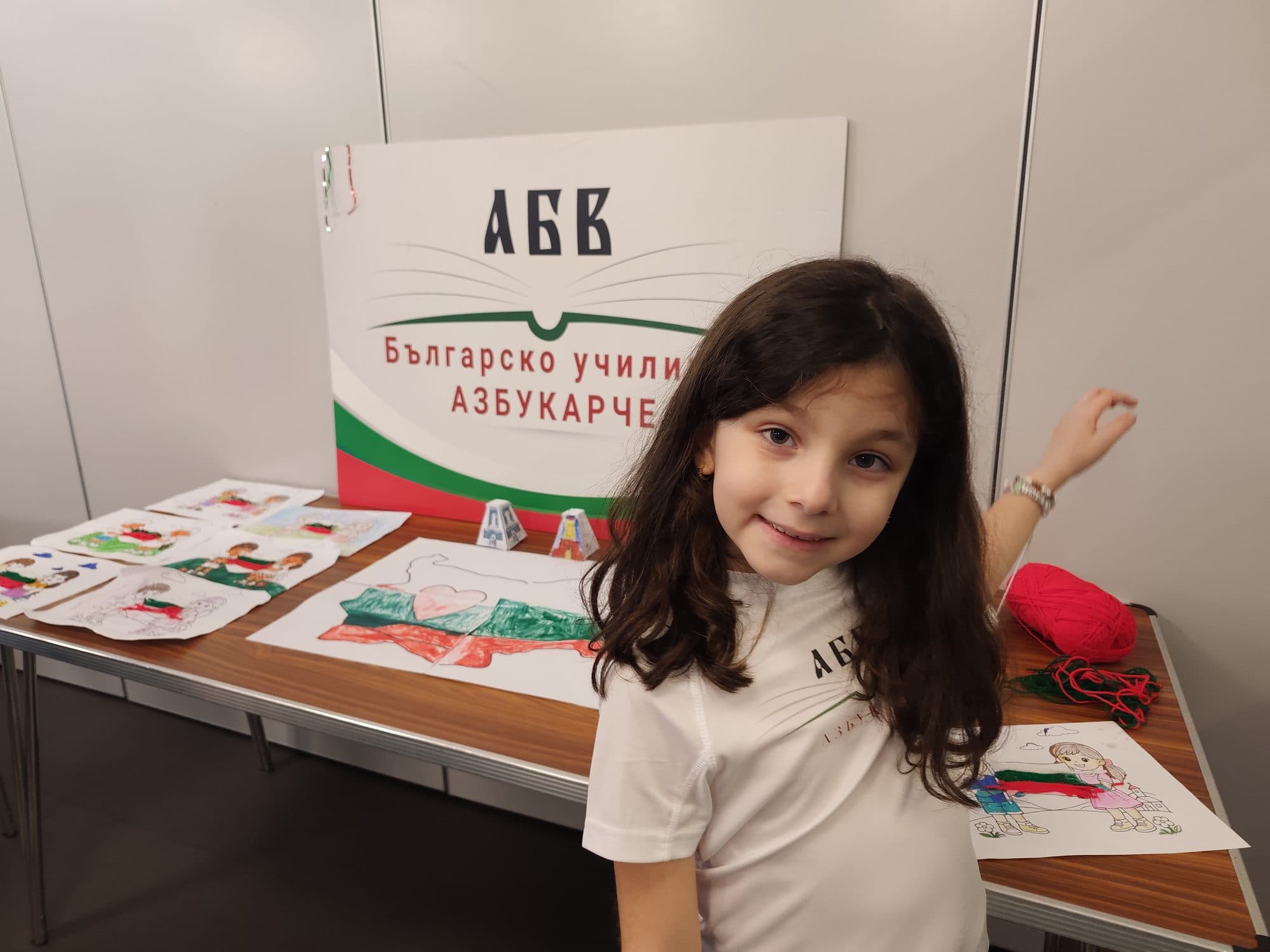 A girl in front of the Azbukarche school display board with children's drawings